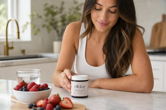 Woman at a bright morning kitchen counter with fresh berries and a glass of water, representing a digestive enzymes with probiotics wellness routine