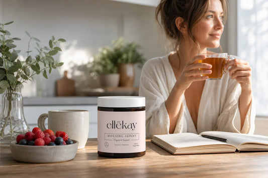 Woman sitting at a sunlit kitchen table with a warm mug of herbal tea, fresh berries, and an open journal, soft morning light, gut health and anxiety wellness routine