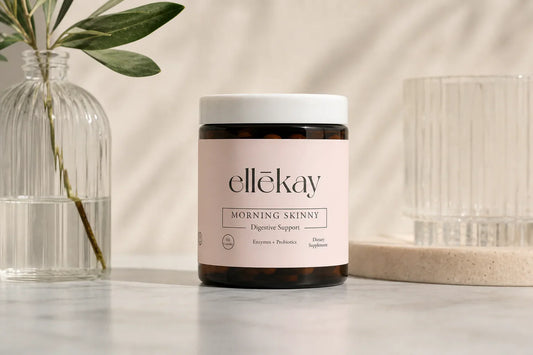 Glass of morning wellness drink on a sunlit kitchen counter with botanical ingredients and skincare products nearby representing gut health and skin